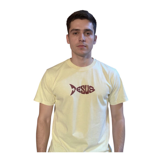 Young man wearing beige colored Jesus, fish Christian T-shirt with bronze colored embroidered text against a white wall